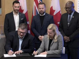 Ontario Power Generation senior vice president Paul Séguin and Port Hope mayor Olga Hankivsky sign a memorandum of understanding (MOU) at the Nuclear Discovery Centre in Port Hope on February 12, 2026 to advance what would be the world's largest nuclear power plant, located in Wesleyville. (kawarthaNOW screenshot of Ontario government video)