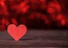A red wooden heart on a dark background. (Stock photo)