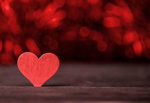 A red wooden heart on a dark background. (Stock photo)