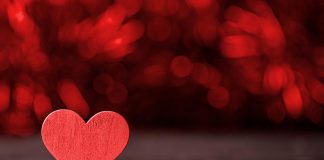 A red wooden heart on a dark background. (Stock photo)