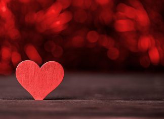 A red wooden heart on a dark background. (Stock photo)