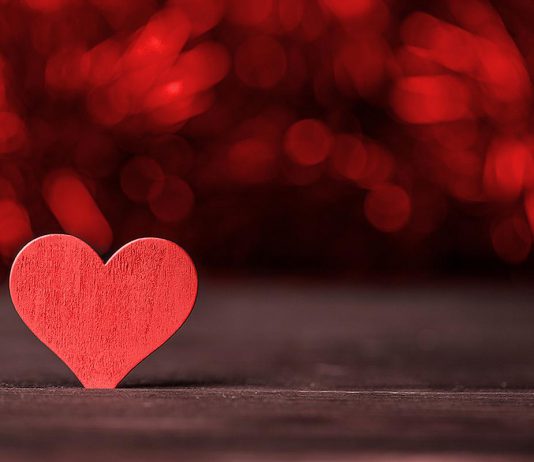 A red wooden heart on a dark background. (Stock photo)