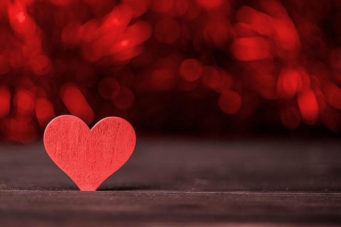 A red wooden heart on a dark background. (Stock photo)