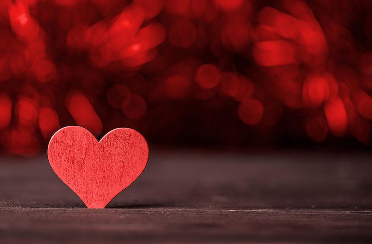A red wooden heart on a dark background. (Stock photo)