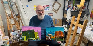 Artist David Geene in his home studio with two 12 by 16 inch paintings of existing buildings that will be featured in his "Economies of Scale?" solo exhibit at Watson & Lou in downtown Peterborough from April 4 to 25, 2026. Titled (left to right) "196 Hunter Street East" and "212 Brock Street from Hunter W. and Aylmer Streets," the works are two of the 12 acrylic paintings that aim to explore the politics and ethics of two proposed high-rise structures in Peterborough, at 90 Hunter Street and on Crescent Street. Including interpretations of the proposed buildings, the exhibit will launch with an opening reception from 2 to 4 p.m. on Saturday, April 4. (Photo courtesy of David Geene)