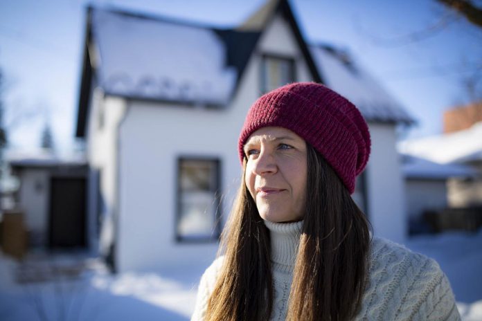 Kat Senyk in front of her upgraded home in Port Perry. Through her work experience leading exterior insulation and finish system (EIFS) overcladding projects, she was inspired to retrofit her own home's exterior insulation, contributing to a nearly 50 per cent reduction in energy use. (Photo: Adrian Merrit Smith)