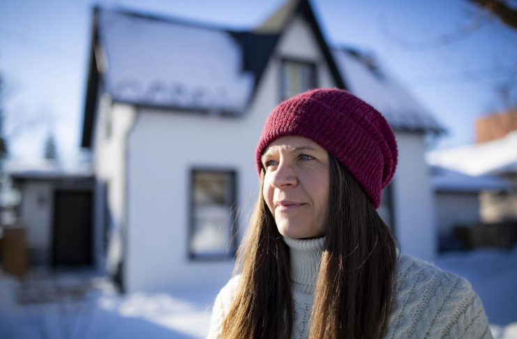 Kat Senyk in front of her upgraded home in Port Perry. Through her work experience leading exterior insulation and finish system (EIFS) overcladding projects, she was inspired to retrofit her own home's exterior insulation, contributing to a nearly 50 per cent reduction in energy use. (Photo: Adrian Merrit Smith)