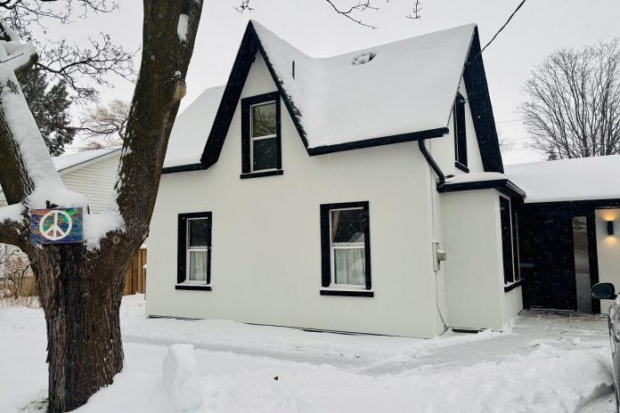 Kat Senyk's retrofitted home retains the home's historic traits while adding exterior insulation, sealing air leaks, and reducing energy use. The home is finished in an off-white stucco with window frames in black and retains the existing finials and soffits. (Photo: Kat Senyk)