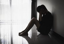 A silhouette of a distressed young woman sitting on the floor. (Stock photo)