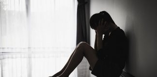 A silhouette of a distressed young woman sitting on the floor. (Stock photo)