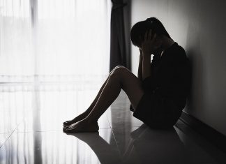 A silhouette of a distressed young woman sitting on the floor. (Stock photo)