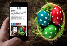 A mobile phone showing kawarthaNOW's Easter 2026 holiday hours over a table with a basket of decorated Easter eggs. (Photo: kawarthaNOW)