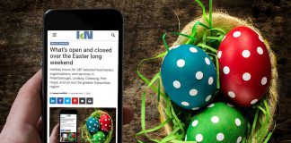 A mobile phone showing kawarthaNOW's Easter 2026 holiday hours over a table with a basket of decorated Easter eggs. (Photo: kawarthaNOW)