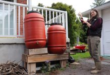 Installing a rain barrel is a simple way to collect water for outdoor use while reducing the amount of water entering local storm sewers. Rain barrels can be connected in a series to detain and collect even more runoff. GreenUP landscape program manager Hayley Goodchild demonstrates how to link rain barrels together at a residential property. (Photo: Jessica Todd / GreenUP)
