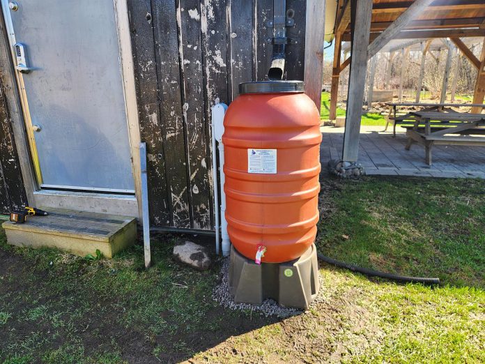 A rain barrel at Ecology Park in Peterborough. A properly installed rain barrel includes a mosquito screen and an overflow hose to direct water away from nearby foundations. It is important to ensure the ground or platform underneath the barrel is level before connecting it to a downspout. (Photo: Hayley Goodchild / GreenUP)