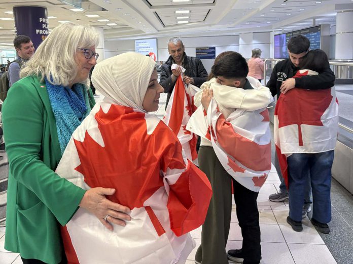 Sponsor Kristy Hiltz with her arm around Rashid Sheikh Hassan's mother while Rashid's brother (middle) hugs sponsor Simal Iftikhar and Rashid (right) hugs one of his sisters, as sponsor Matt Park (back left) looks on and Rashid's father (back middle) holds a Canadian flag, after the Hassan family at Toronto's Pearson International Airport on April 24, 2026 to join their son in Peterborough. (Photo courtesy of Dave McNab)