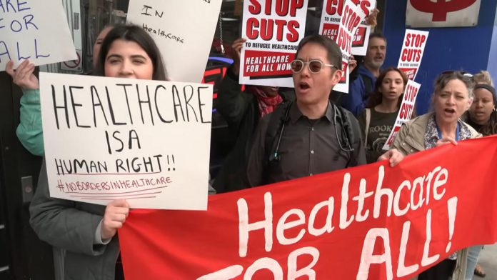 A protest in Toronto on April 14, 2026 against changes to the Interim Federal Health Program (IFHP) that would require refugees to begin paying fees for some healthcare services starting May 1. (kawarthaNOW screenshot of CBC video) A protest in Toronto on April 14, 2026 against changes to the Interim Federal Health Program (IFHP) that would require refugees to begin paying fees for some healthcare services starting May 1. (kawarthaNOW screenshot of CBC video)
