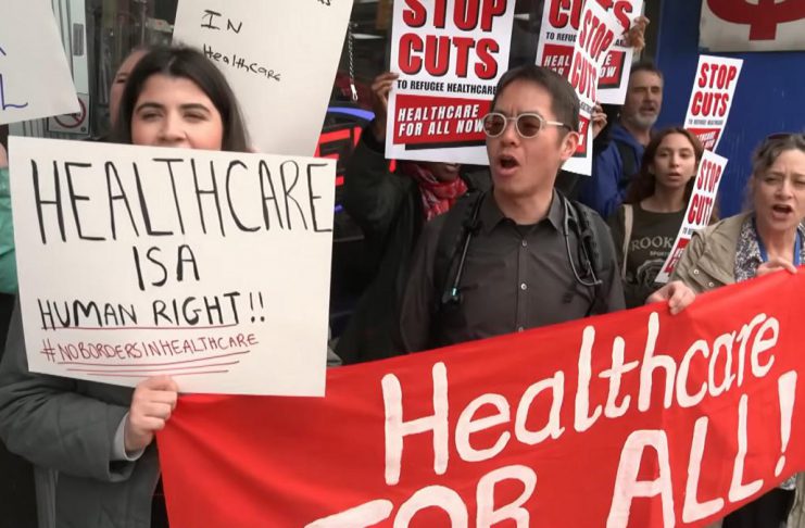 A protest in Toronto on April 14, 2026 against changes to the Interim Federal Health Program (IFHP) that would require refugees to begin paying fees for some healthcare services starting May 1. (kawarthaNOW screenshot of CBC video)