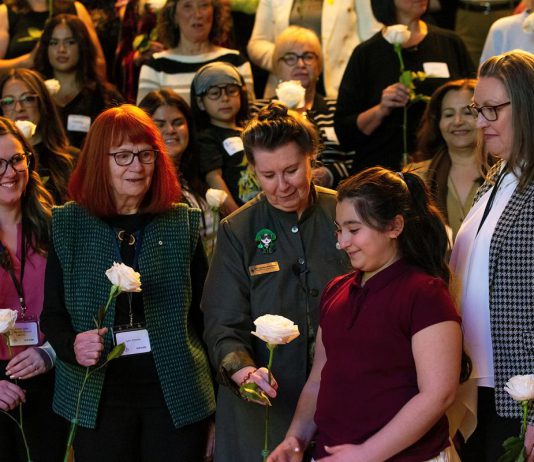 Peterborough Community Health Centre executive director Ashley Safar, former YWCA Peterborough Haliburton executive director Lynn Zimmer, Senator Marilou McPhedran, Maryam Monsef's niece Ellia, and Kawartha Financial Services senior manager of commercial solutions Darlene Weales hold white roses in memory of the late Peterborough civic leader Ann Farquharson during the "A Conversation About The Status of Women In Our Community" event at Market Hall in downtown Peterborough on March 31, 2026, presented by Maryam Monsef's organization ONWARD in partnership with the Peterborough and Kawarthas Chamber of Commerce, which featured 16 female speakers engaging in conversation on important issues related to women's health, resilience, and leadership. (Photo: Jordan Lyall / kawarthaNOW)