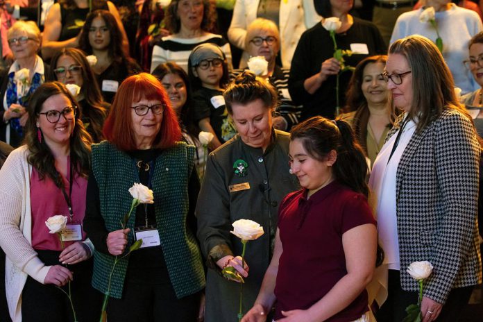 Peterborough Community Health Centre executive director Ashley Safar, former YWCA Peterborough Haliburton executive director Lynn Zimmer, Senator Marilou McPhedran, Maryam Monsef's niece Ellia, and Kawartha Financial Services senior manager of commercial solutions Darlene Weales hold white roses in memory of the late Peterborough civic leader Ann Farquharson during the "A Conversation About The Status of Women In Our Community" event at Market Hall in downtown Peterborough on March 31, 2026, presented by Maryam Monsef's organization ONWARD in partnership with the Peterborough and Kawarthas Chamber of Commerce, which featured 16 female speakers engaging in conversation on important issues related to women's health, resilience, and leadership. (Photo: Jordan Lyall / kawarthaNOW)