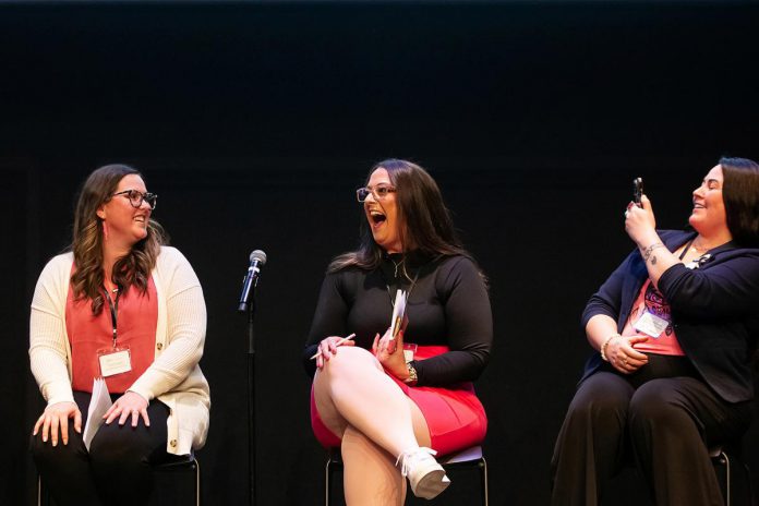 Tiffany Arcari of The Tiffany Show (middle) laughs as Peterborough Community Health Centre executive director Ashley Safar (left) looks on and Curve Lake First Nation singer-songwriter and artist Missy Knott takes a photo during the "A Conversation About The Status of Women In Our Community" event at Market Hall in downtown Peterborough on March 31, 2026, presented by Maryam Monsef's organization ONWARD in partnership with the Peterborough and Kawarthas Chamber of Commerce. (Photo: Jordan Lyall / kawarthaNOW