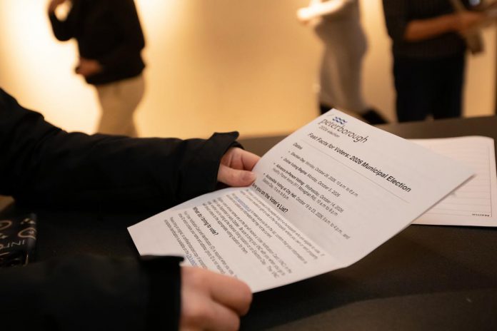 An attendee in the lobby at Market Hall Performing Arts Centre in downtown Peterborough reviews a "Fast Facts for Voters" handout from the City of Peterborough during the "So, You Want to Run for Council - Candidate 101 Information Session" on March 31, 2026. (Photo: Jordan Lyall / kawarthaNOW)