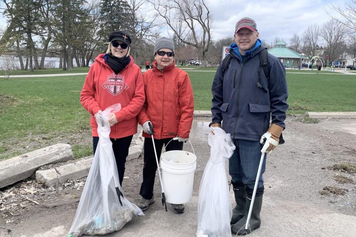 Three of the 35-plus volunteers who participated in an Earth Day clean-up of Rogers Cove park in Peterborough on April 19, 2026, picking up litter along the Little Lake waterfront and in the park. The clean-up was organized by Becca Durbin, owner of Salix Environmental Consulting, in partnership with Clean Up Peterborough and the City of Peterborough. (Photo: Bethan Bates / kawarthaNOW)