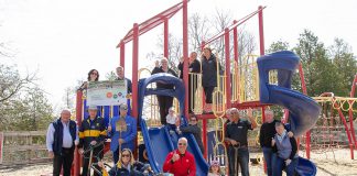 The Rotary Club of Peterborough and Riverview Park and Zoo celebrated early major donors for the new Rotary Accessible Playground during an event at the zoo on April 22, 2026, and also revealed a mockup of a donor recognition wall that will be installed when the $1.5 million project is constructed. Pictured are donors at the existing play structure at the zoo. (Photo: Jordan Lyall / kawarthaNOW)