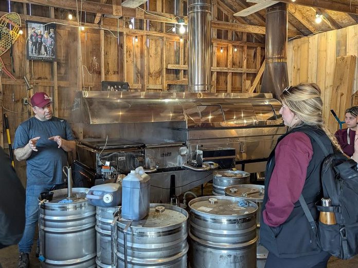 Red Mill Maple Syrup co-owner Sebastien Poulin (left) leads a tour about maple syrup production at the Millbrook producer's sugar shack. He and his wife Julie Vallieres, who were both raised in a region of Quebec well-known for maple syrup, have been producing maple syrup at their 10-acre property since 2011 and launched the Red Mill Maple Syrup brand in 2017. The business is a member of Kawartha Choice FarmFresh to promote their products to consumers and is interested in participating in the Kawartha Local Food Wholesale program to reach more wholesale buyers. (Photo courtesy of Red Mill Maple Syrup) Red Mill Maple Syrup co-owner Sebastien Poulin (left) leads a tour about maple syrup production at the Millbrook producer's sugar shack. He and his wife Julie Vallieres, who were both raised in a region of Quebec well-known for maple syrup, have been producing maple syrup at their 10-acre property since 2011 and launched the Red Mill Maple Syrup brand in 2017. The business is a member of Kawartha Choice FarmFresh to promote their products to consumers and is interested in participating in the Kawartha Local Food Wholesale program to reach more wholesale buyers. (Photo courtesy of Red Mill Maple Syrup)