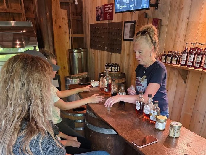 Red Mill Maple Syrup co-owner Julie Vallieres (right) serves guests during a maple syrup tasting in the Millbrook producer's sugar shack. She and her husband Sebastien Poulin sell all-natural maple syrup and host educational tours and tastings on site, with the goal of bringing Quebec's love of maple syrup to The Kawarthas. (Photo courtesy of Red Mill Maple Syrup)