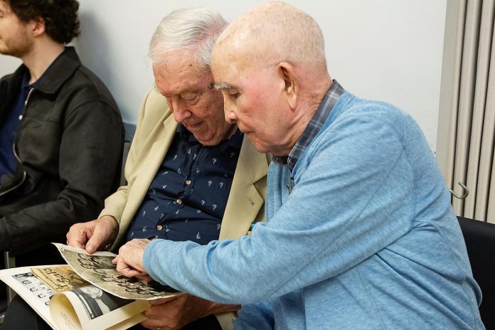James Clarke (left) and Murray Byrne look through old photos during a rehearsal for Trent Valley Archives Theatre's "The Kid from Simcoe Street," based on Clarke's memoir of the same title. The reunion marked the first time the duo had seen each other in more than 70 years, since they were football teammates while attending St. Peter Catholic Secondary School in Peterborough. (Photo: Jordan Lyall Photography)
