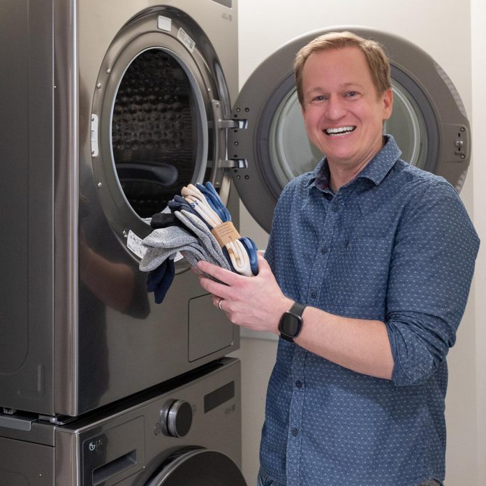 Craig Mortlock, co-owner of MCI Constructors Inc., poses with the washer and dryer at the Peterborough Community Health Centre funded by a $30,000 donation from his company, which also allow the centre to outfit a new community kitchen. (Photo courtesy of Peterborough Community Health Centre)