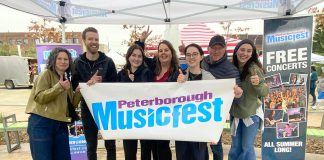 The Peterborough Musicfest team, led by executive director Tracey Randall (middle), celebrating the lineup of free-admission summer outdoor concerts for the festival's 39th season during an announcement event at Quaker Foods City Square in downtown Peterborough on May 13, 2026. (Photo: Paul Rellinger / kawarthaNOW)