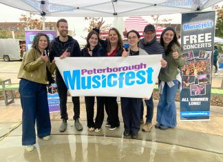 The Peterborough Musicfest team, led by executive director Tracey Randall (middle), celebrating the lineup of free-admission summer outdoor concerts for the festival's 39th season during an announcement event at Quaker Foods City Square in downtown Peterborough on May 13, 2026. (Photo: Paul Rellinger / kawarthaNOW)