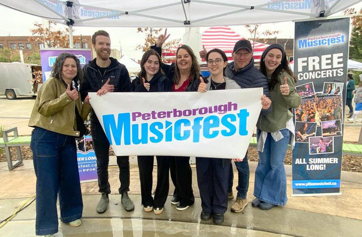 The Peterborough Musicfest team, led by executive director Tracey Randall (middle), celebrating the lineup of free-admission summer outdoor concerts for the festival's 39th season during an announcement event at Quaker Foods City Square in downtown Peterborough on May 13, 2026. (Photo: Paul Rellinger / kawarthaNOW)