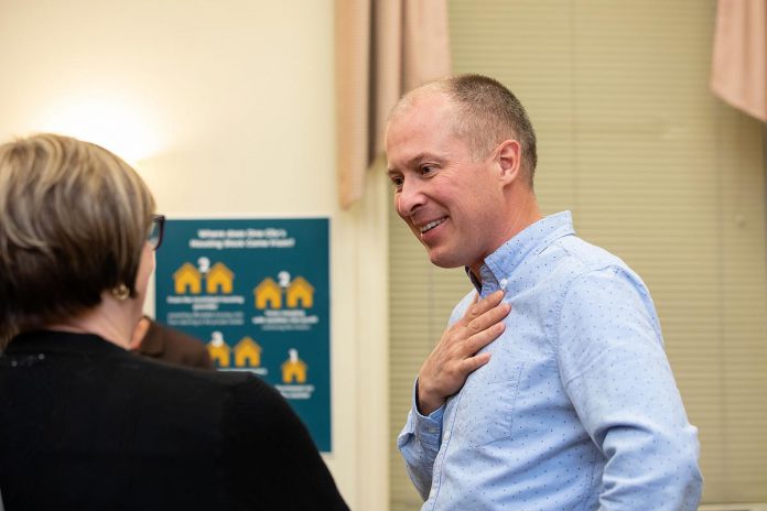 Michael VanDerHerberg, director of property development at One City Peterborough, speaks to an attendee during an event to discuss the non-profit organization's housing strategy at Knights of Columbus Hall on May 12, 2026. (Photo: Jordan Lyall / kawarthaNOW)