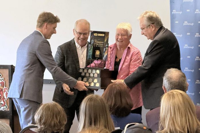 With the help of Peterborough city councillor Kevin Duguay and Mayor Jeff Leal, city clerk John Kennedy presents Mary Jane Smith with the Volunteer of the Year award during the 2025 Civic Awards ceremony at the McDonnel Street Community Centre on May 21, 2026. (Photo: City of Peterborough)