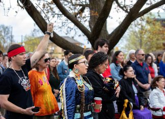 Residents of Nogojiwanong-Peterborough gathered at Peterborough City Hall on May 5, 2026 to commemorate Red Dress Day at an event led by the Urban Indigenous Working Group in collaboration with the City of Peterborough. May 5 has been recognized as the National Day of Awareness for Missing and Murdered Indigenous Women, Girls, and 2SLGBTQI+ People (MMIWG2S+) since 2010. (Photo: Jordan Lyall / kawarthaNOW)