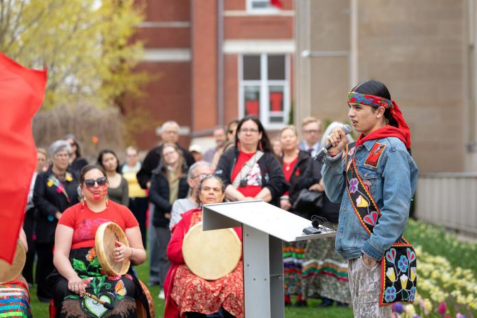 Kelvin Boissoneau, an 18 year old from Garden River First Nation near Sault Ste. Marie, led attendees in an opening prayer and song during an event to commemorate Red Dress Day at Peterborough City Hall on May 5, 2026. (Photo: Jordan Lyall / kawarthaNOW)