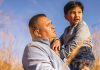 Alto’s Commitment to Indigenous Peoples An Indigenous man holding a boy in his arms with a field in the background. (Photo: Alto)