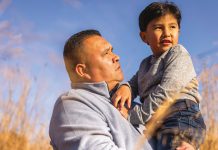 Alto’s Commitment to Indigenous Peoples An Indigenous man holding a boy in his arms with a field in the background. (Photo: Alto)