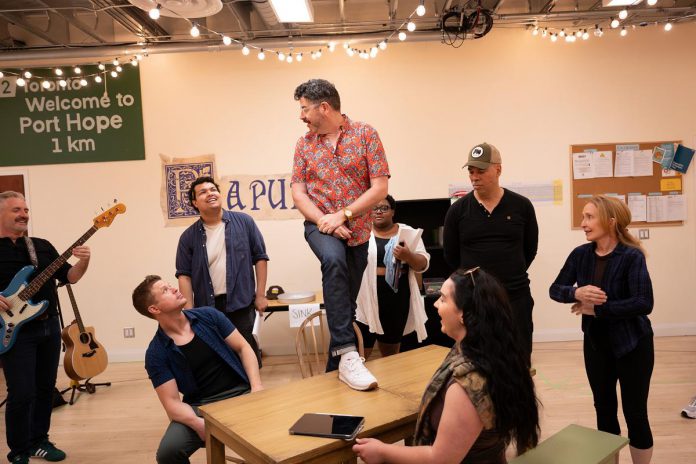Capitol Theatre artistic director Rob Kempson (standing on the table) directing the cast during a rehearsal of the Capitol Theatre's production of "Come From Away" at the historic venue in Port Hope from July 10 to August 9, 2026. (Photo: Sam Moffatt)