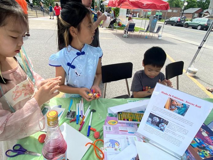 During the Block Party event held during the 2024 Canadian Multicultural Festival hosted by the New Canadians Centre (NCC), children gather around a vendor booth that's all about Pakistan, hosted by NCC client and volunteer Saima Sarfraz. Alongside offering activities around Pakistan's truck art, the booth invited kids to learn about how most of the world's soccer balls, including those used in the World Cup, are made in Sialkot, Pakistan. (Photo courtesy of Saima Sarfraz)
