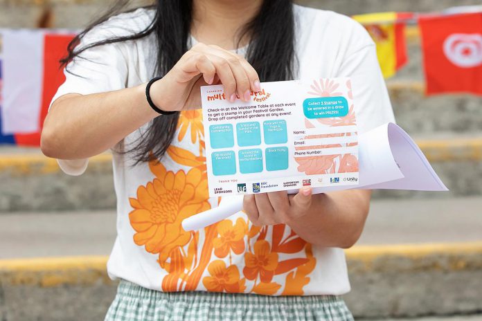 The New Canadians Centre's Fund Development Officer Asuka Ballantyne displays the Festival Garden passport during an announcement on June 10, 2026 of the fifth annual Canadian Multicultural Festival. Once you collect three or more stamps from a welcome table at each event during the festival, you can submit the passport to be entered in a draw to win prizes. (Photo: Jordan Lyall / kawarthaNOW)