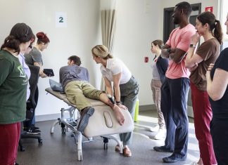 Trent Health in Motion sports medicine physician Dr. Jessica Hewitt shows her colleagues how to use a portable ultrasound unit during a team in-service, illustrating the clinic's integrated and collaborative approach with a focus on evidence-informed healthcare. Located within the Trent University Athletics Centre in Peterborough, Trent Health in Motion provides personalized care for sports rehabilitation, injury recovery, and overall wellness, with services including orthopedic physiotherapy, pelvic physiotherapy, chiropractic care, massage therapy, personal training, dietitian services, hydrotherapy, and sport medicine physician consultations. (Photo courtesy of Trent Health in Motion)