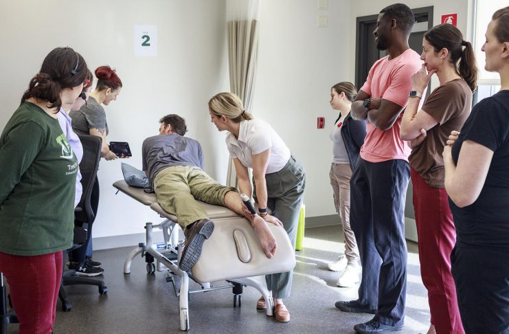 Trent Health in Motion sports medicine physician Dr. Jessica Hewitt shows her colleagues how to use a portable ultrasound unit during a team in-service, illustrating the clinic's integrated and collaborative approach with a focus on evidence-informed healthcare. Located within the Trent University Athletics Centre in Peterborough, Trent Health in Motion provides personalized care for sports rehabilitation, injury recovery, and overall wellness, with services including orthopedic physiotherapy, pelvic physiotherapy, chiropractic care, massage therapy, personal training, dietitian services, hydrotherapy, and sport medicine physician consultations. (Photo courtesy of Trent Health in Motion)