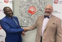 The United Way of Peterborough and District's incoming CEO Jason Seguya shakes hands with retiring CEO Jim Russell during an announcement at the United Way's office on June 18, 2026. The 27-year-old will begin in his new role on July 6, with Russell staying until July 17 to help with the transition. (Photo: Paul Rellinger / kawarthaNOW)