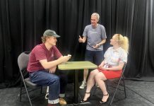 Director Jack van Roosmalen (standing) with actors Eddy Sweeney and Rebecca Birrell during a rehearsal for "Photographic Memory" written by Ron Davies. The 10-minute play, about a man who finds that photos can be as hard as memories to erase after his ex asks him to delete some photos she sent him, is one of 10 plays to be staged as part of the "10 Minute Sunday" short play festival hosted by the Peterborough Theatre Guild on August 9, 2026. (Photo courtesy of D'Arcy Jenish)