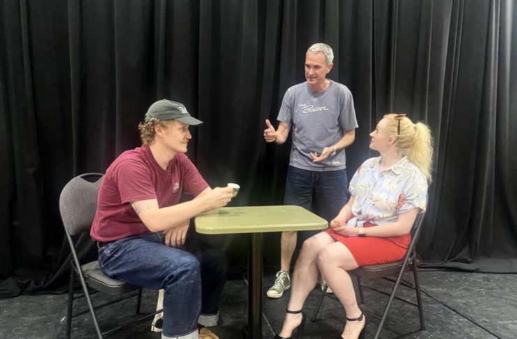 ’10 Minute Sunday’ short play festival returns to the Peterborough Theatre Guild on August 9 Director Jack van Roosmalen (standing) with actors Eddy Sweeney and Rebecca Birrell during a rehearsal for "Photographic Memory" written by Ron Davies. The 10-minute play, about a man who finds that photos can be as hard as memories to erase after his ex asks him to delete some photos she sent him, is one of 10 plays to be staged as part of the "10 Minute Sunday" short play festival hosted by the Peterborough Theatre Guild on August 9, 2026. (Photo courtesy of D'Arcy Jenish)