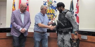 Cobourg police service board chair Adam Bureau (left) and retired sergeant Don Missen, who led the Cobourg police's former canine unit from 1997 to 2003, presented Constable Amrit Gill and German shepherd Atos with the K-9 badge at a ceremony during the police service board's meeting in council chambers at Victoria Hall on July 28, 2026. (Photo courtesy of Cobourg Police Service)